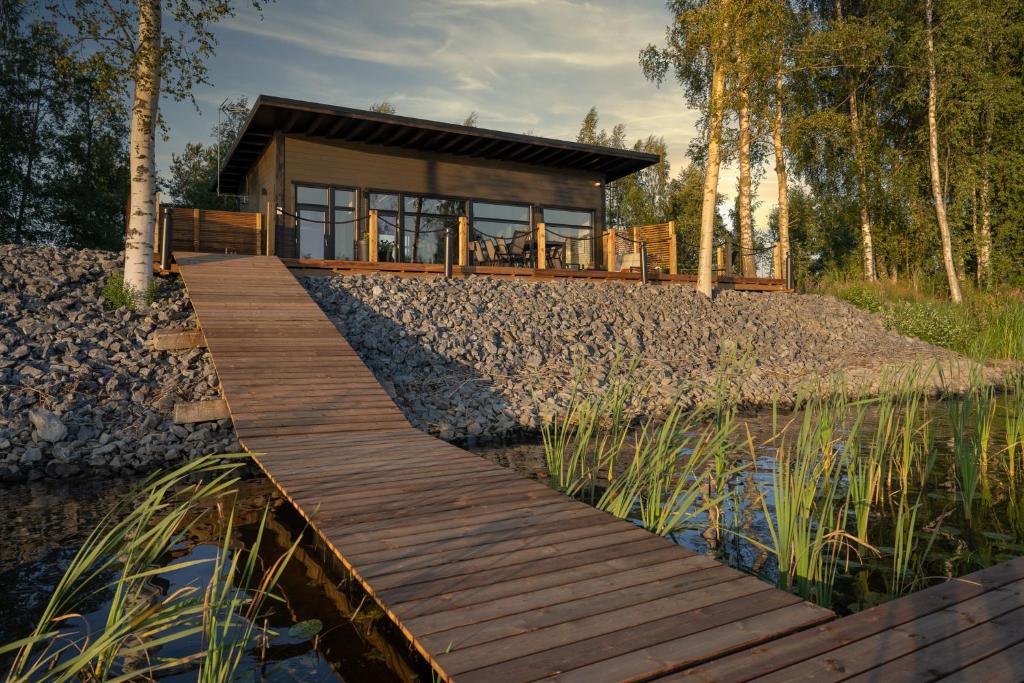 uma ponte de madeira sobre um lago em frente a uma casa em Villa Suisto em Pori