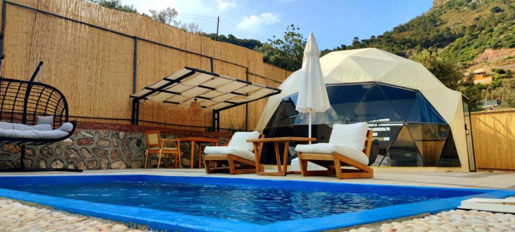 a tent with chairs and a table and a swimming pool at Kabak Freedom Deluxe Hotel in Faralya