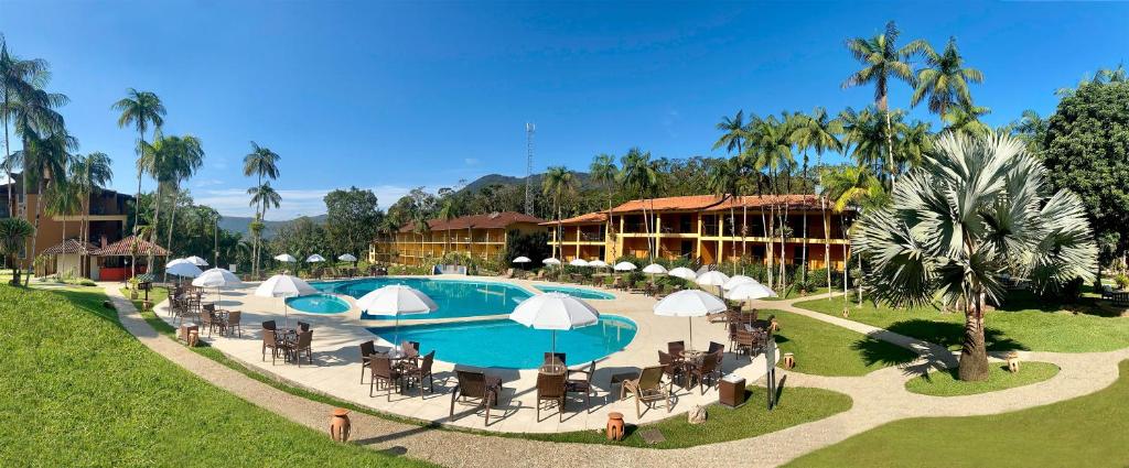 um resort com uma piscina com cadeiras e guarda-sóis em Hotel Fazenda Vale das Pedras em Jaraguá do Sul