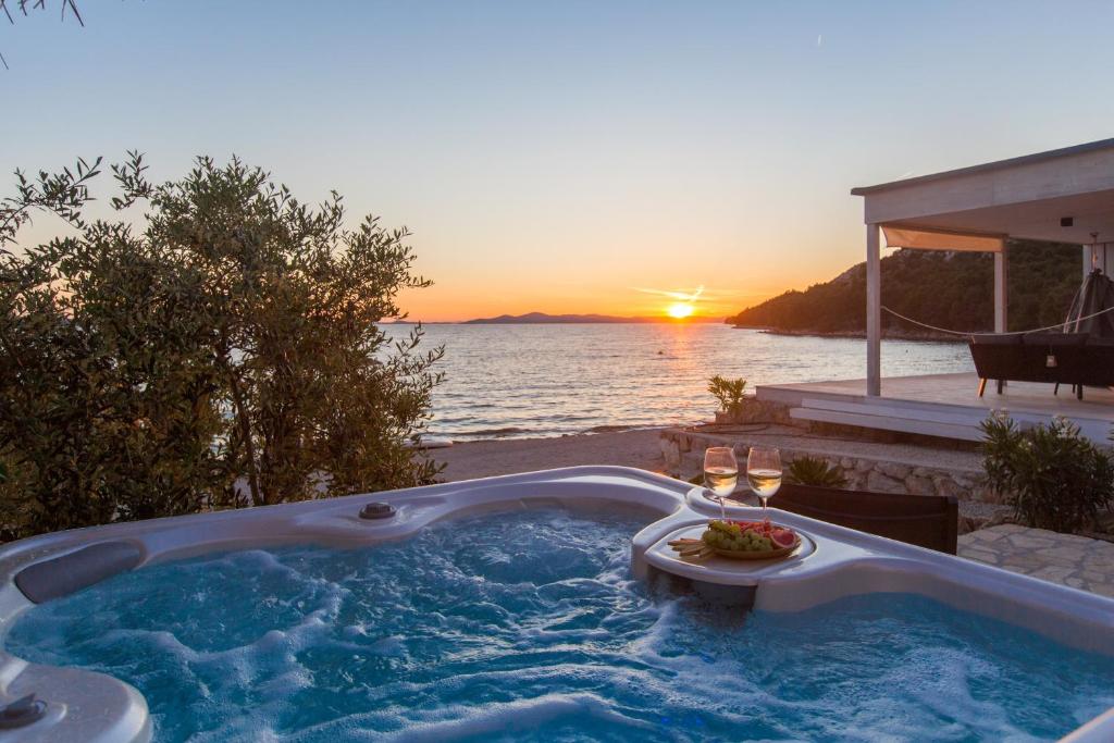 une baignoire jacuzzi avec un coucher de soleil en arrière-plan dans l'établissement Luxury Home Buqez No 18, à Drage