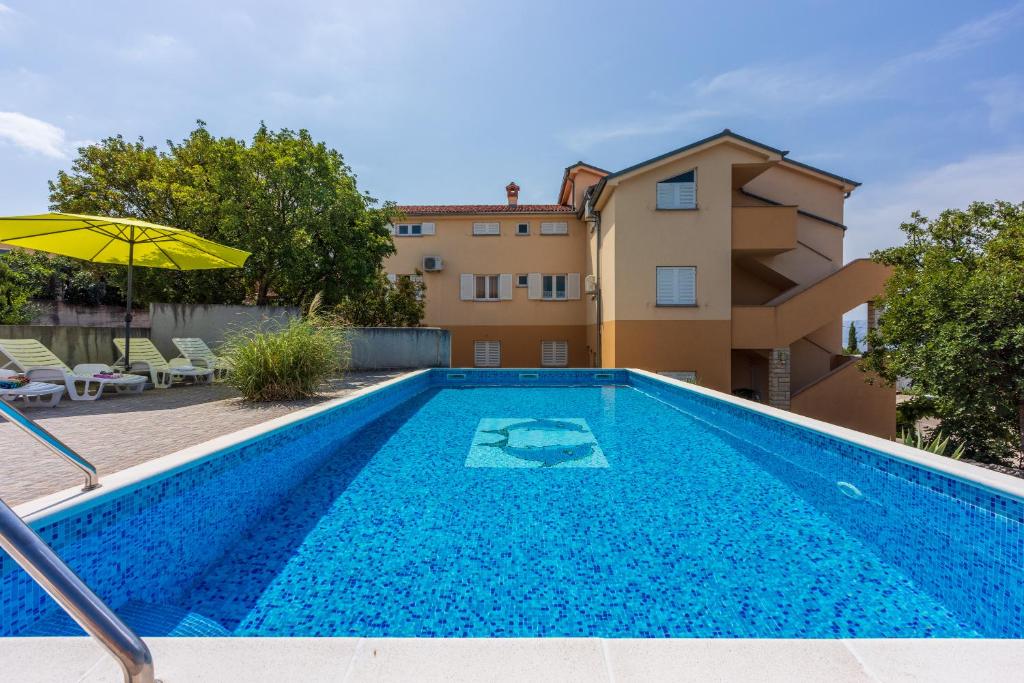 a swimming pool in front of a villa at Apartmani Jarić in Novi Vinodolski