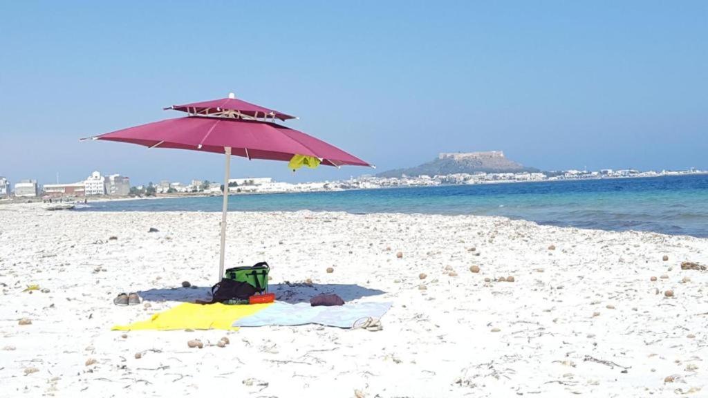 a beach with an umbrella on the sand at Diar Mira in Kelibia