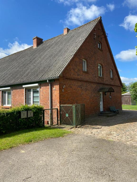 a red brick house with a gate in front of it at FeWo Maila in Flemendorf