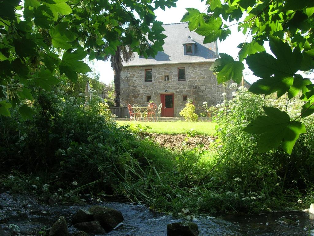 an old stone house with a red door and a stream at ancien moulin à eau entièrement rénové in Prat