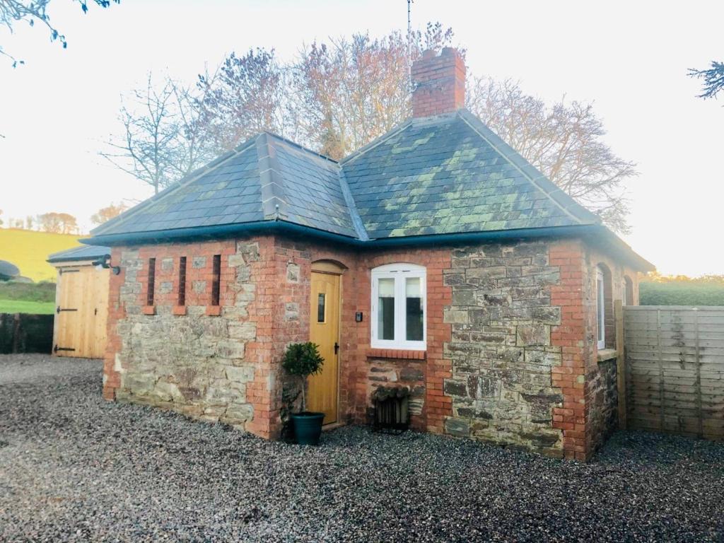 una pequeña casa de ladrillo con puerta amarilla en The Outhouse - Cosy Country Guest Suite, en Kingston