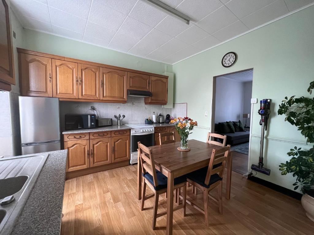 a kitchen with wooden cabinets and a wooden table with chairs at Centre ville - Maison chaleureuse - 6 pers in Châteaubriant