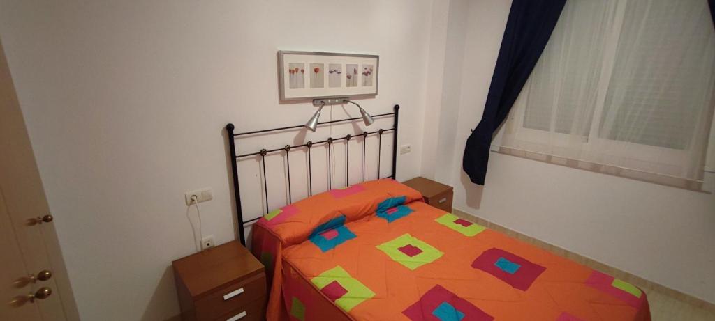 Dormitorio pequeño con cama y edredón colorido en Costa de Marfil I-SERVHOUSE, en Castellón de la Plana