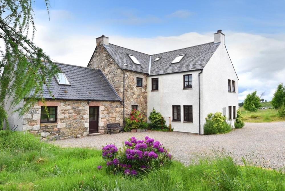 een groot stenen huis met een grindoprit bij The Press House in Carrbridge