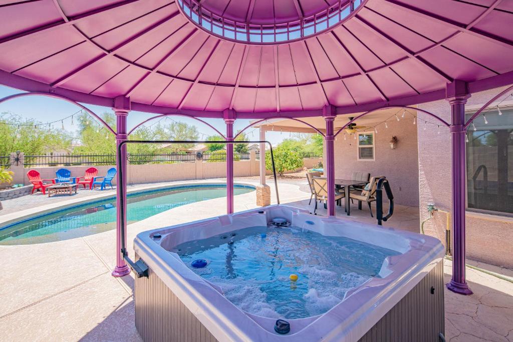 a hot tub under a pink umbrella next to a pool at Boho Chic Arizona Villa w Pool & Mini Golf in Casa Grande