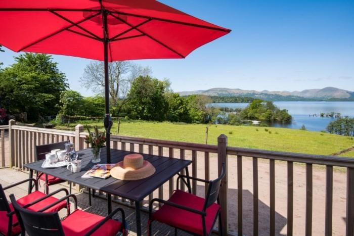 a table and chairs with a red umbrella on a deck at The Old Farmhouse in Balloch