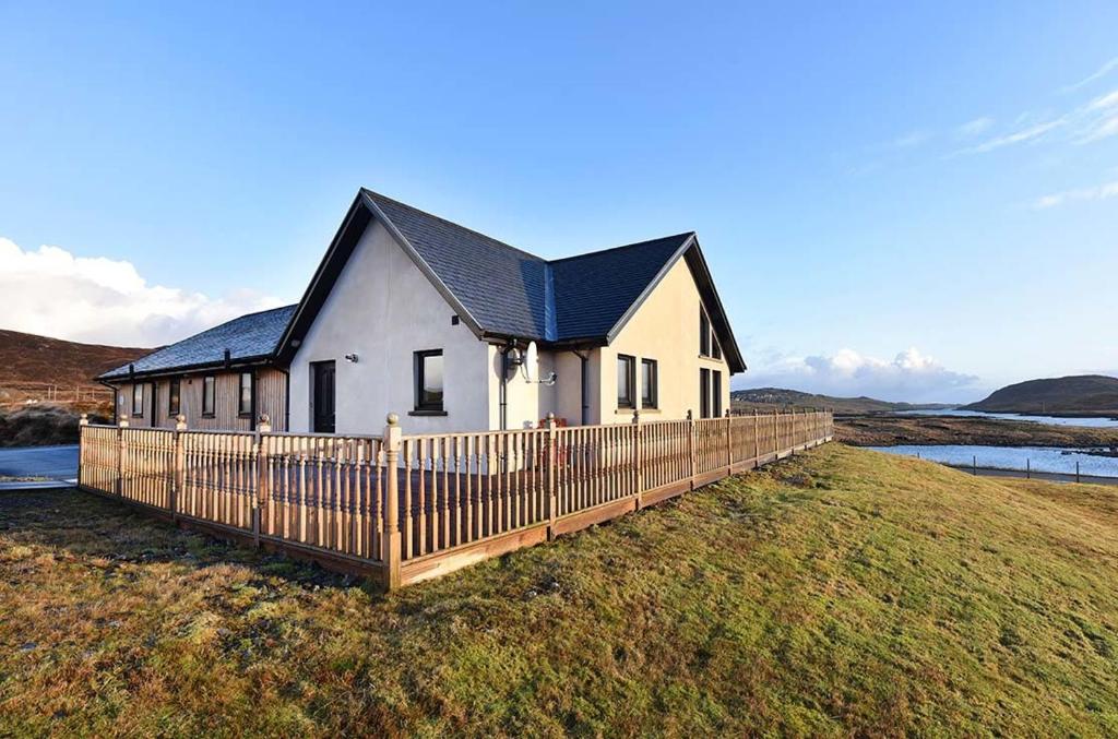 ein Haus mit einem Holzzaun davor in der Unterkunft Ceann an Loch Cottage in Balallan