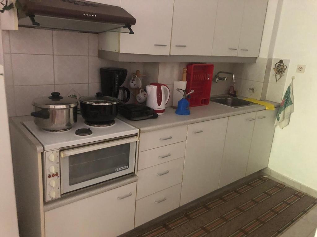 a small kitchen with white cabinets and a stove at The square in Mariaí