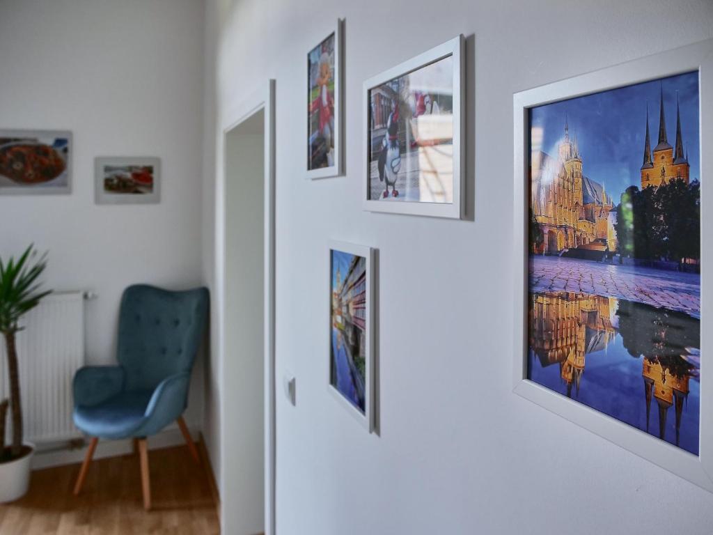 een hal met een blauwe stoel en foto's aan de muur bij Appartement SCHILLER I - Erfurt Zentrum in Erfurt