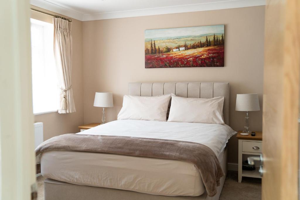 una camera da letto con un letto e un dipinto sul muro di The Cedars a West Clandon