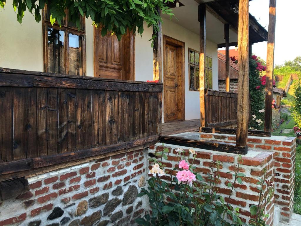 a porch of a house with a wooden fence and flowers at Old Court in Curtea de Argeş