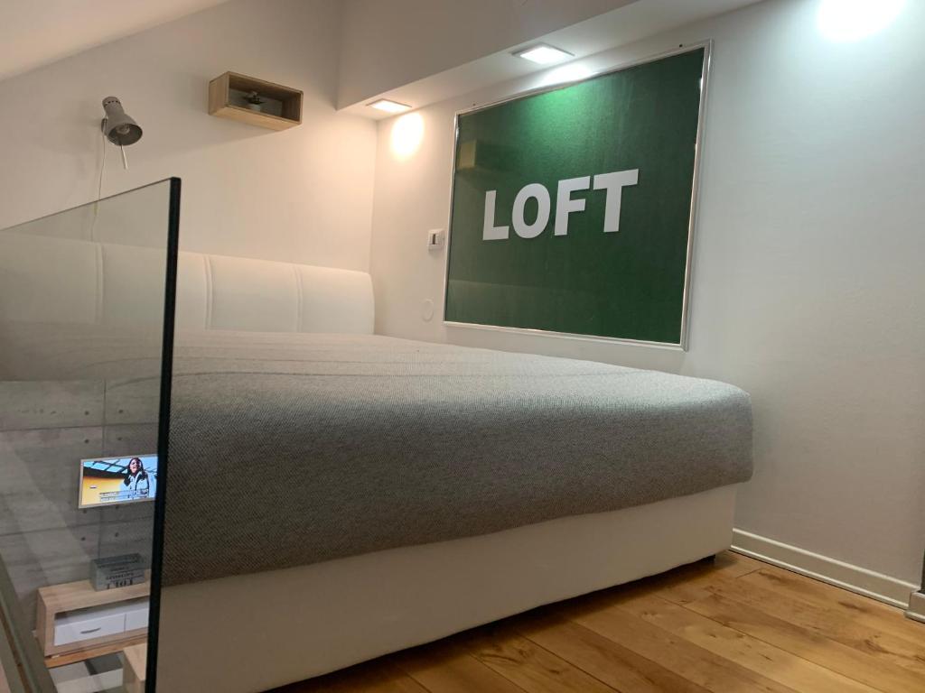 a bed in a room with a sign on the wall at Loft Osijek in Osijek