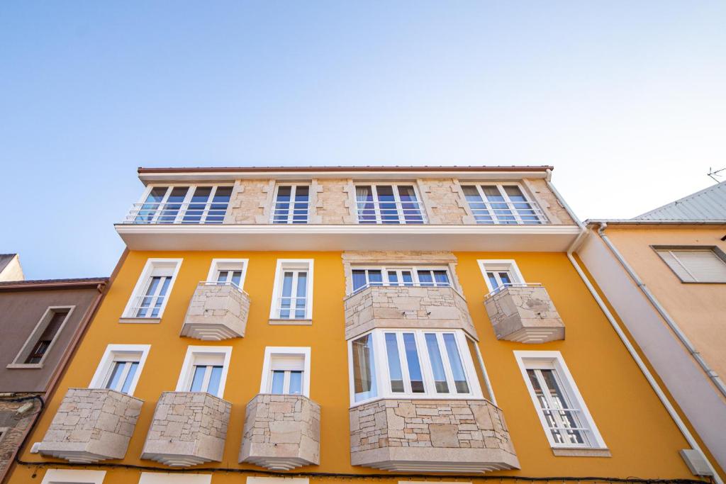 un edificio giallo con finestre bianche e balconi di La Casona 1930 a Mazaricos