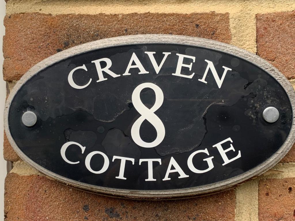 una señal para una taberna y una conferencia en una pared de ladrillo en Craven Cottage, en Northallerton