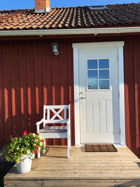 a wooden porch with a white door and a bench at Lillstugan in Skara