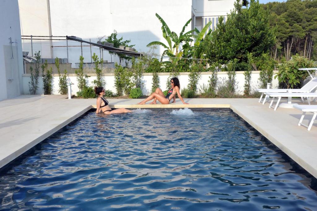 dos chicas sentadas en una piscina en BluOtranto, en Otranto