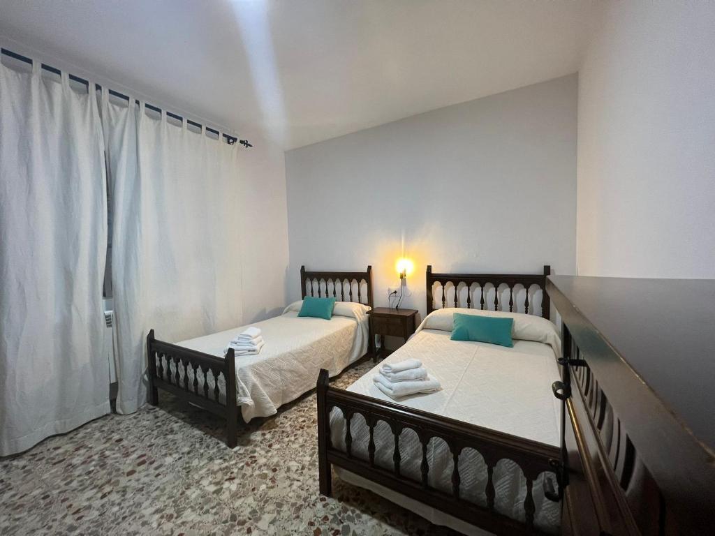 1 dormitorio con 2 camas y ventana en Apartamentos Lalola, en Cabezuela del Valle