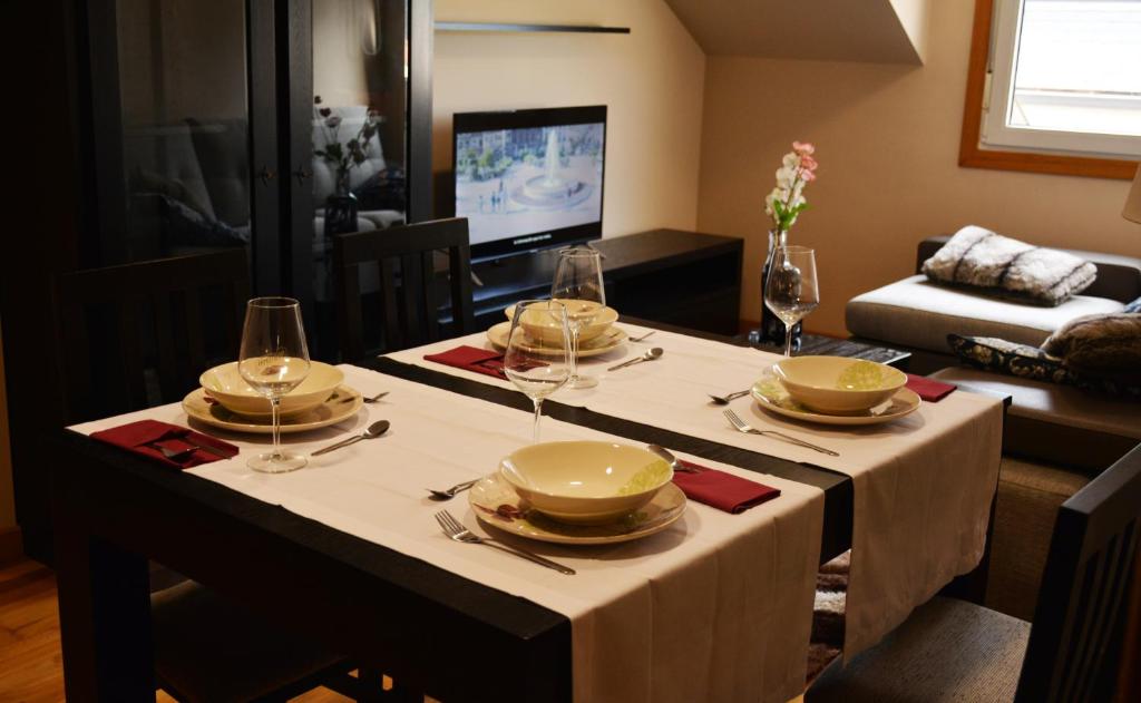 a dining room table with plates and wine glasses on it at Apartamentos Gallaecia in Val do Dubra