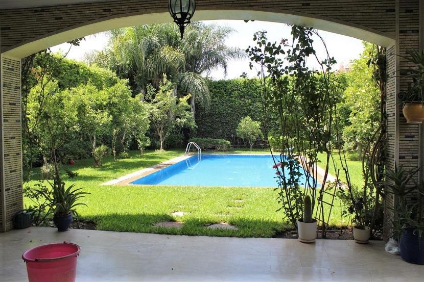 een boog die leidt naar een zwembad in een tuin bij Magnifique villa avec piscine pour famille uniquement in Marrakesh