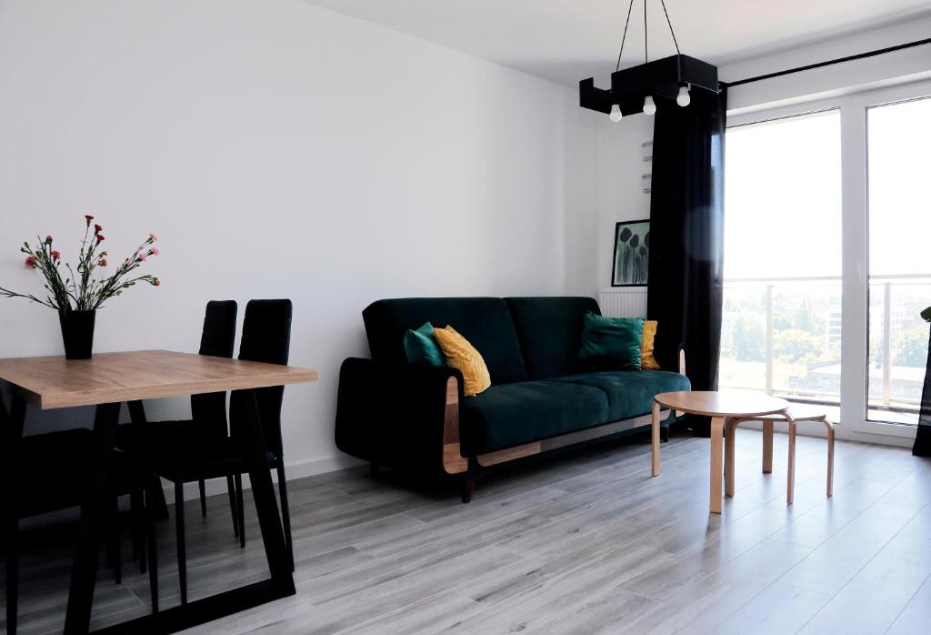 a living room with a green couch and a table at Apartament Tramwajowa 17B in Łódź