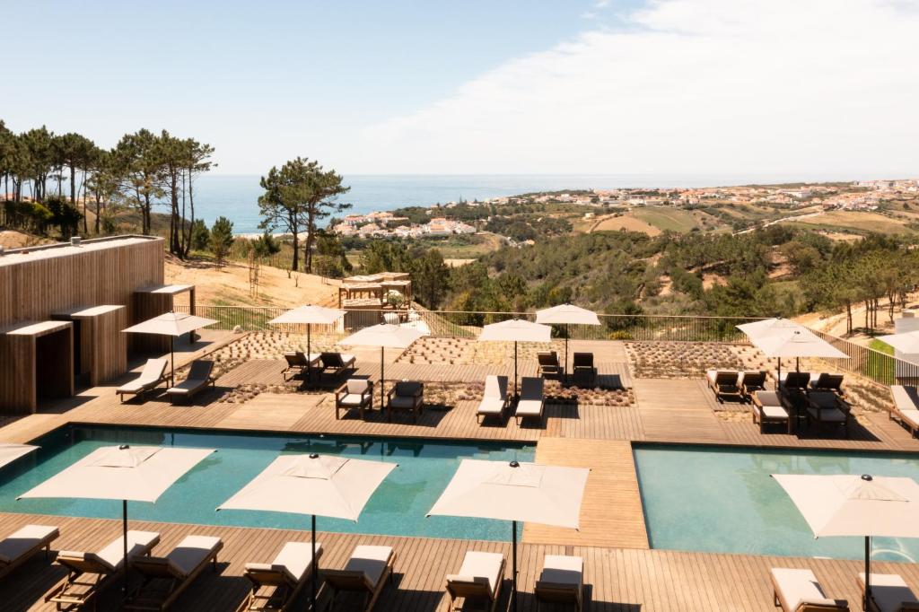 a view of the pool at a resort with chairs and umbrellas at Immerso Hotel, a Member of Design Hotels in Ericeira