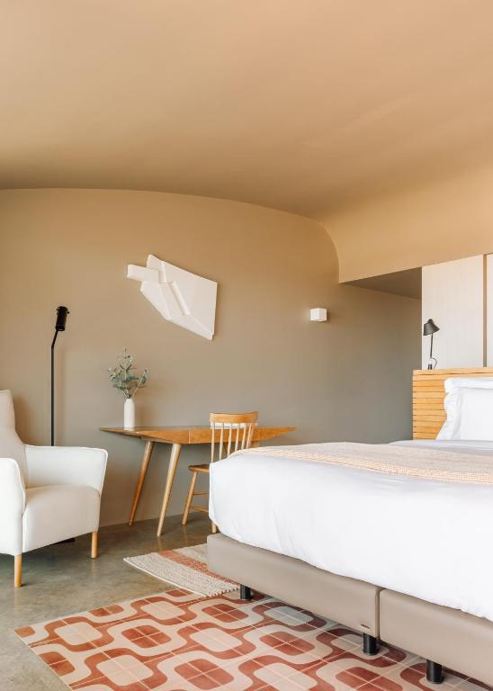 a bedroom with a bed and a table and a chair at Immerso Hotel, a Member of Design Hotels in Ericeira