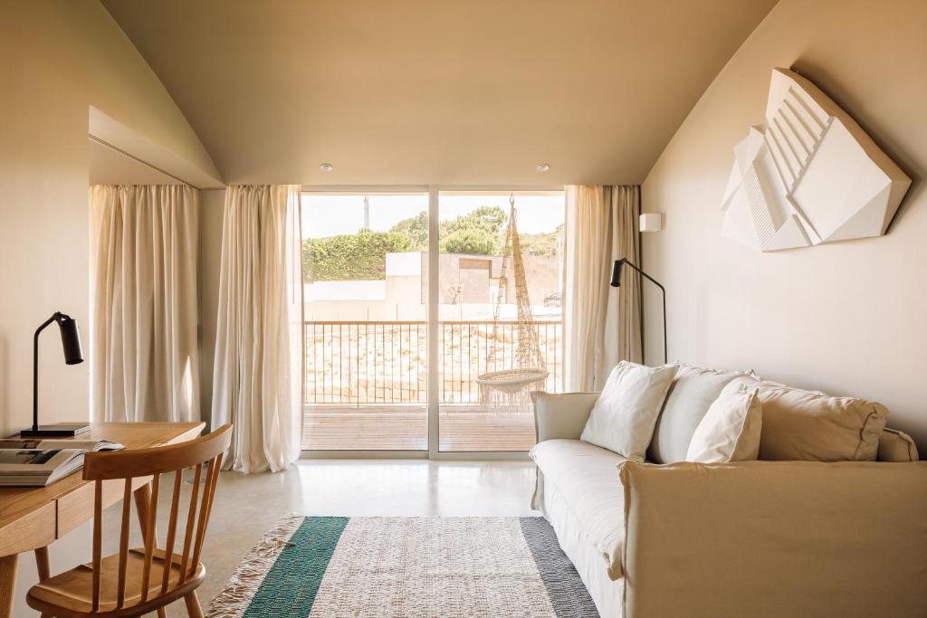a living room with a couch and a table and a desk at Immerso Hotel, a Member of Design Hotels in Ericeira