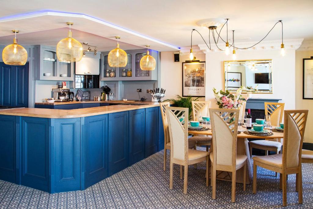 a kitchen with blue cabinets and a table with chairs at Cosy Open Plan Harbourside Inn with SuperKing Beds, Wood Burning Stove and Bar in Torquay