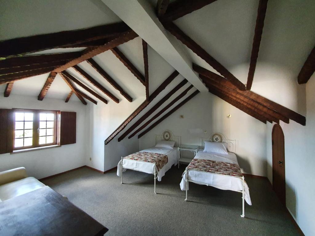 a attic room with two beds and a window at Casa do Cruzeiro in Aguiar da Beira