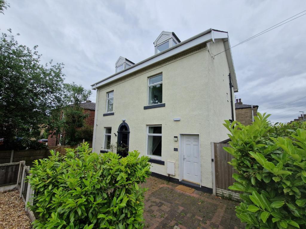 une maison blanche avec une clôture et des buissons dans l'établissement Milne Apartment 2, à Milnrow