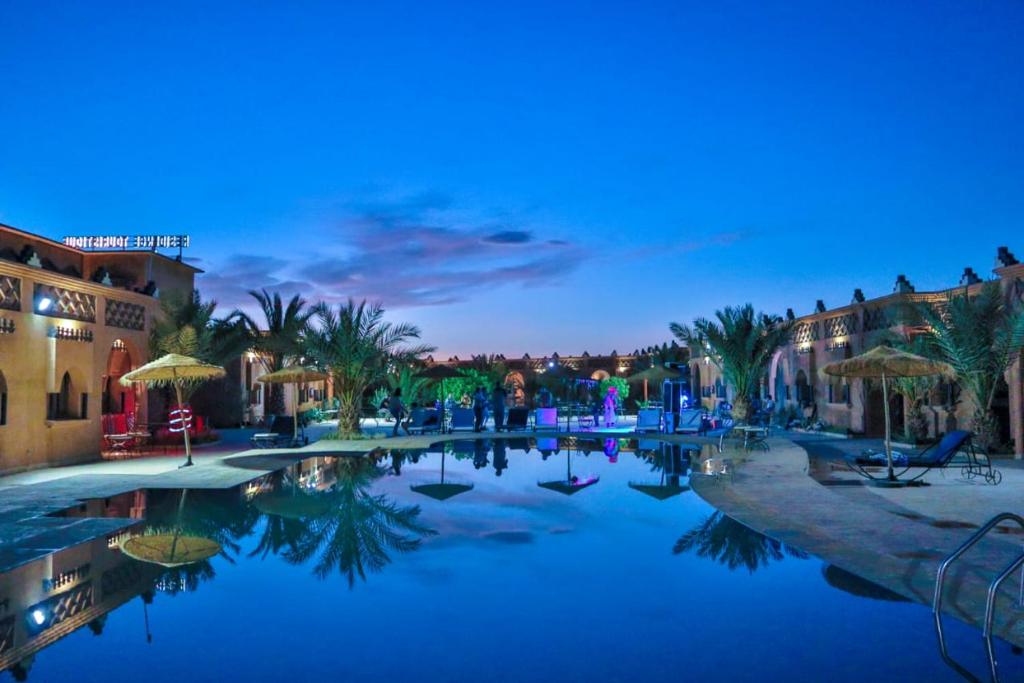 a swimming pool in a resort at night at Residence Touristique Merzouga in Merzouga