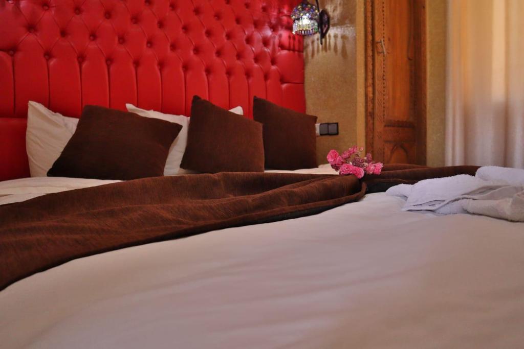 a bedroom with two beds with a red headboard at Residence Touristique Merzouga in Merzouga