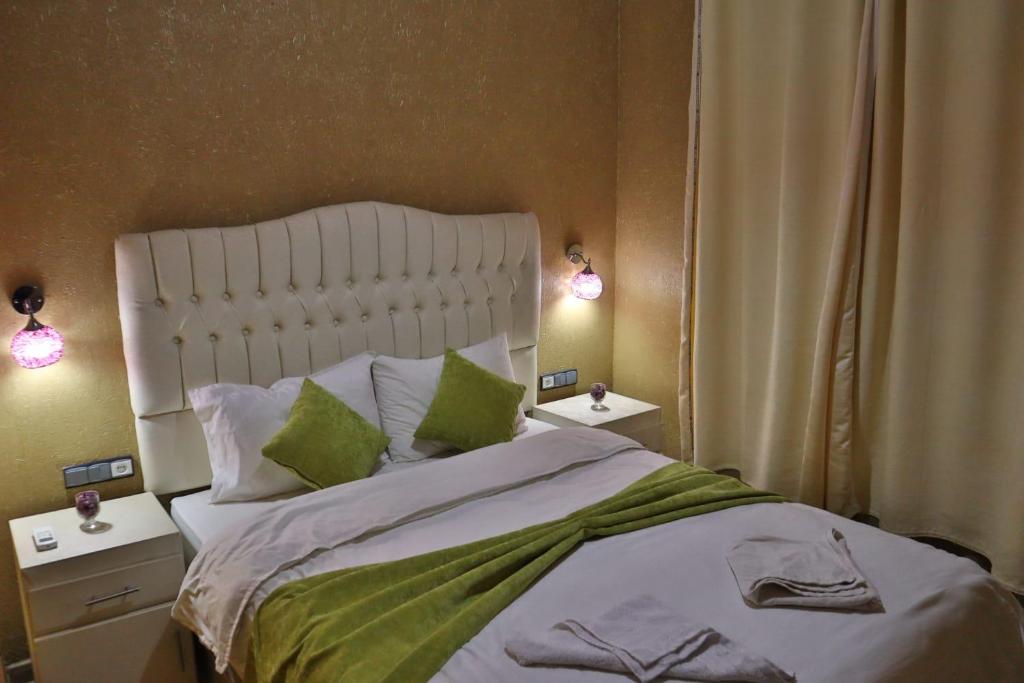 a bedroom with a large white bed with green pillows at Residence Touristique Merzouga in Merzouga