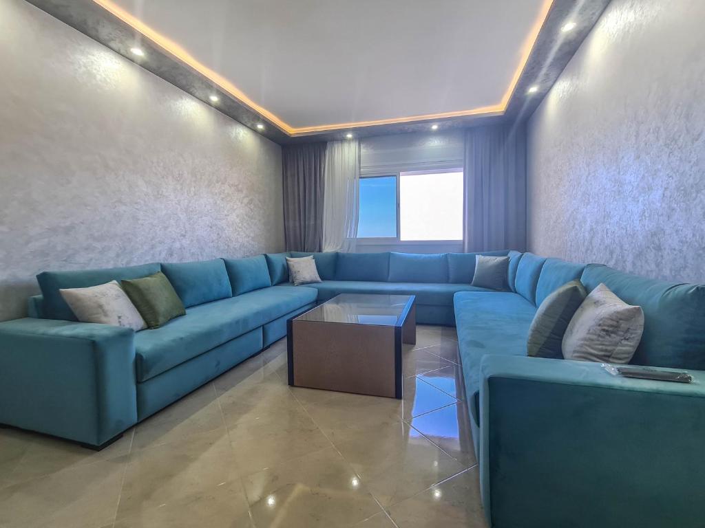 een woonkamer met een blauwe bank en een tafel bij Immeuble Familial Imad in Tetouan