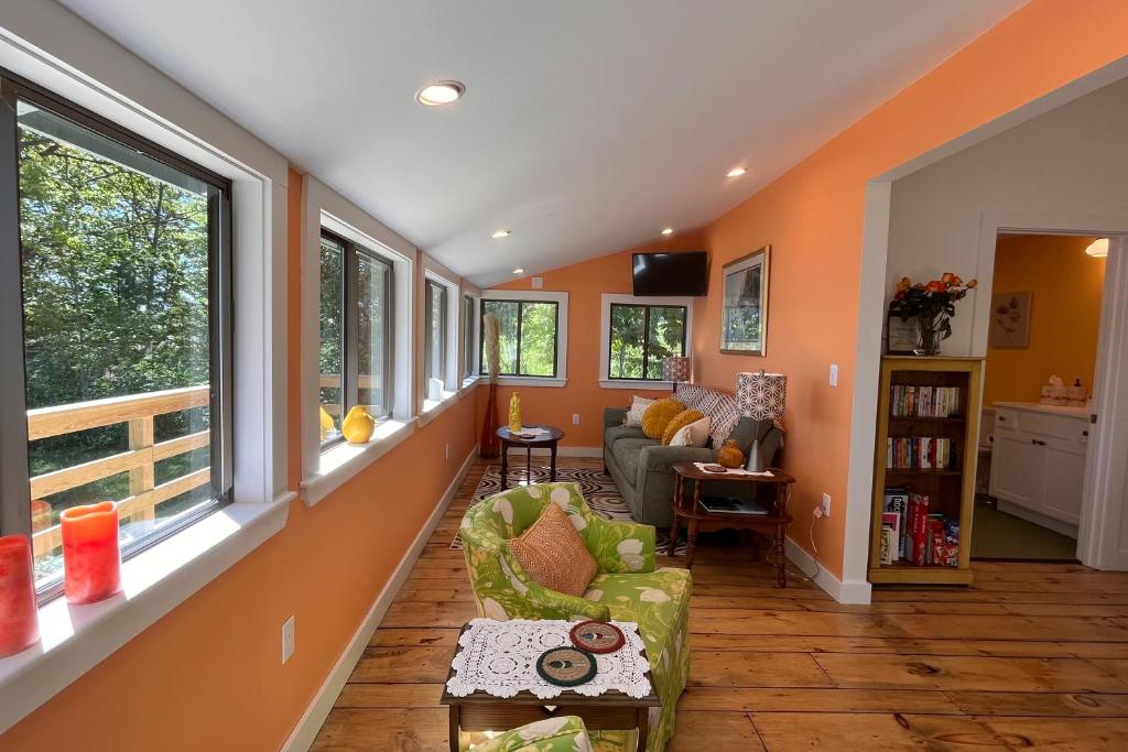 uma sala de estar com paredes cor de laranja e um sofá em Rising Tide Cottage em Cushing