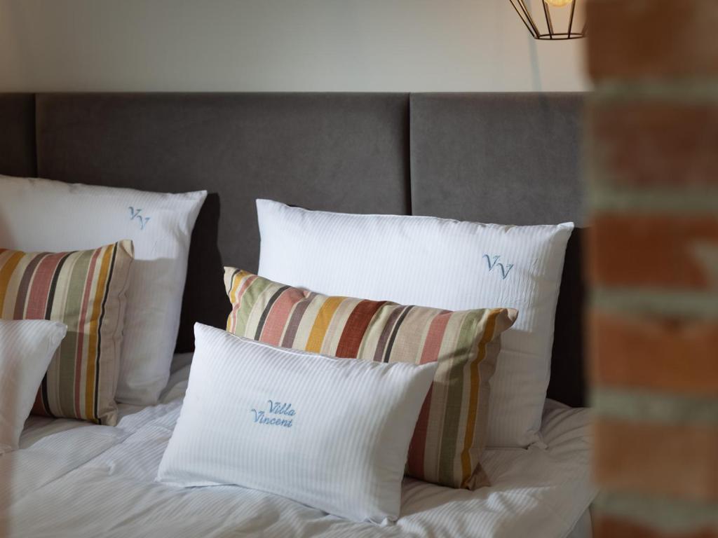 łóżko z białymi poduszkami i szarym zagłówkiem w obiekcie Vincent Apartamenty Darłówek w mieście Darłowo
