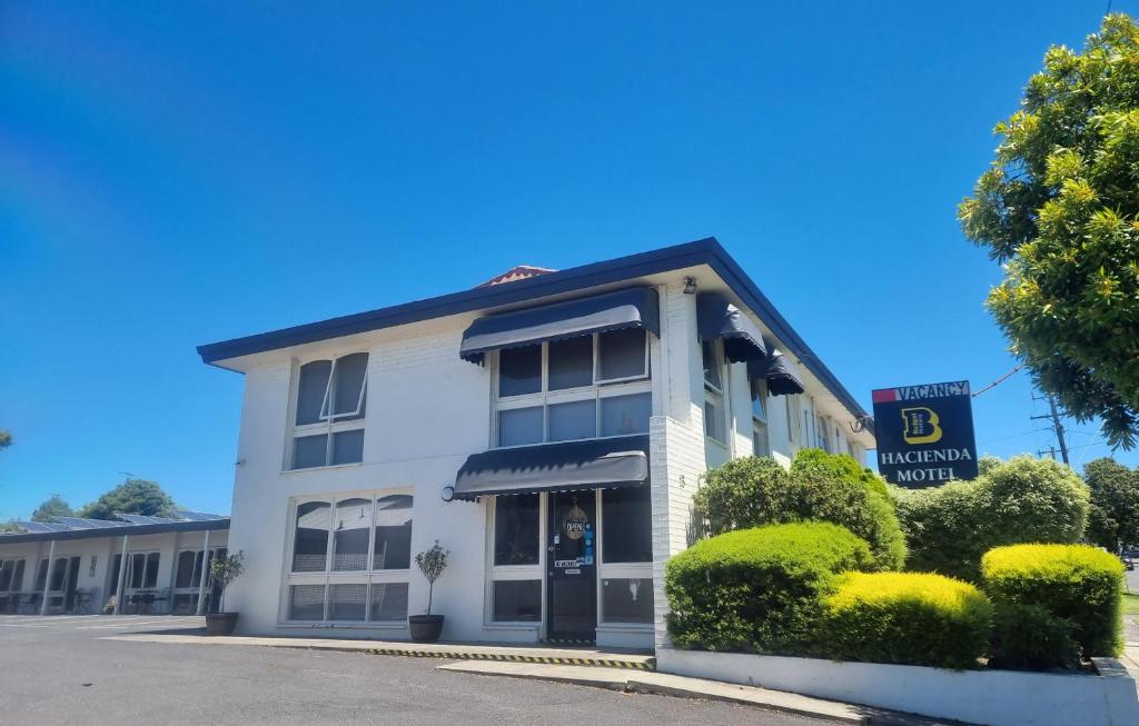 een wit gebouw met een bord met b hotelkamer bij Hacienda Motel Geelong in Geelong