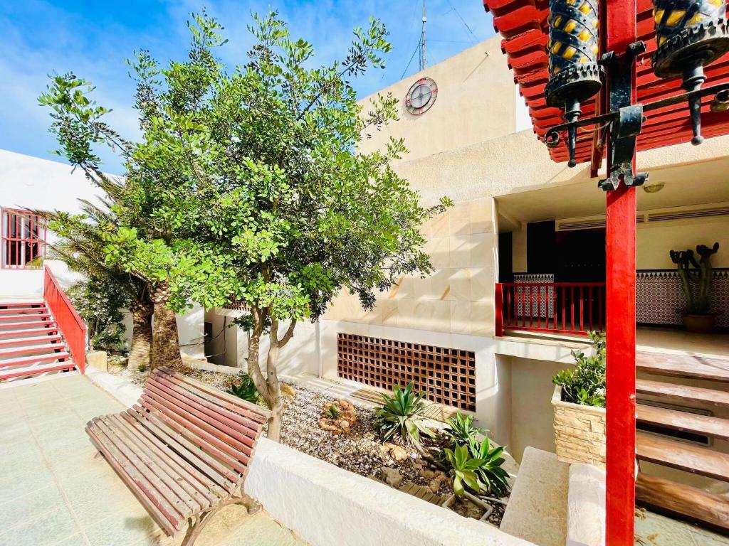 Seafront apartment in La Garrofa near the beach في La Garrofa: مبنى فيه عمود احمر ودرج وشجرة