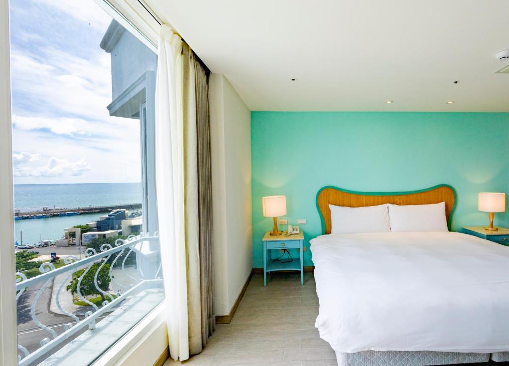 a bedroom with a bed and a large window at Kenting Long Beach Hotel in Checheng