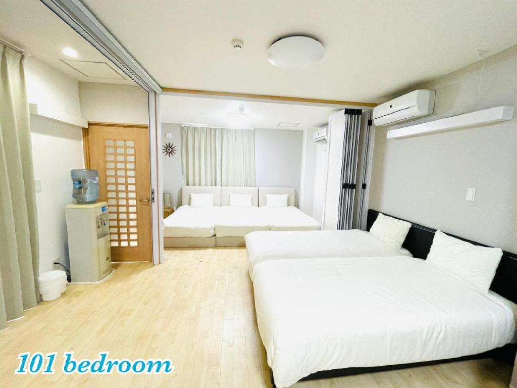 um quarto com 2 camas e um frigorífico em Mcity in Wakasa em Naha