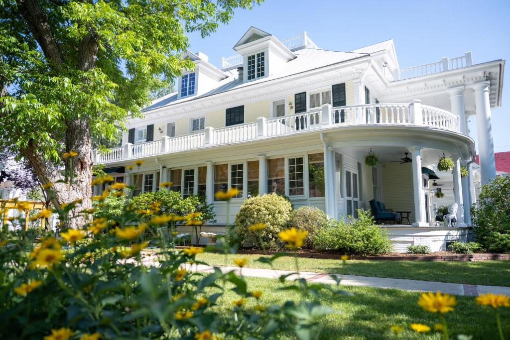 a white house with a porch and yellow flowers at The Edenton Collection-The Granville Queen Inn in Edenton