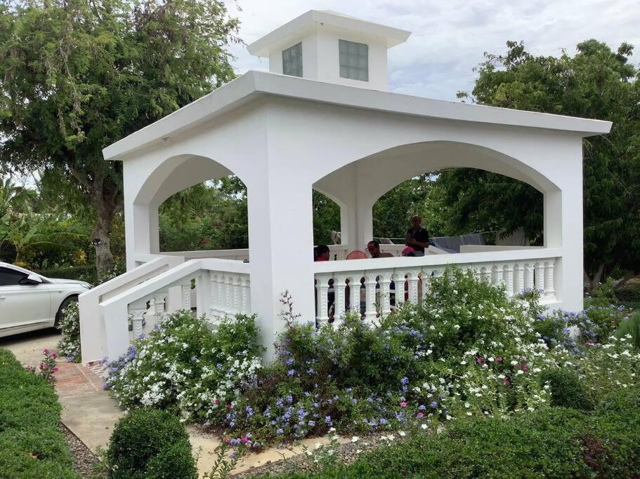 a white gazebo in a garden with flowers at La Casa Blanca 