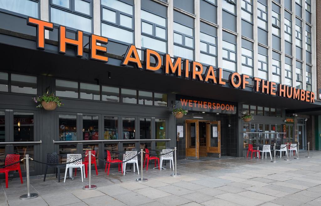 um restaurante com mesas e cadeiras em frente a um edifício em Admiral of the Humber Wetherspoon em Hull