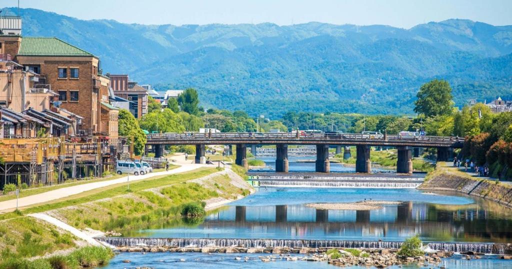 a river in a city with a bridge and mountains at 鴨川 栄の屋 Kamo River Machiya Halo House in Kyoto