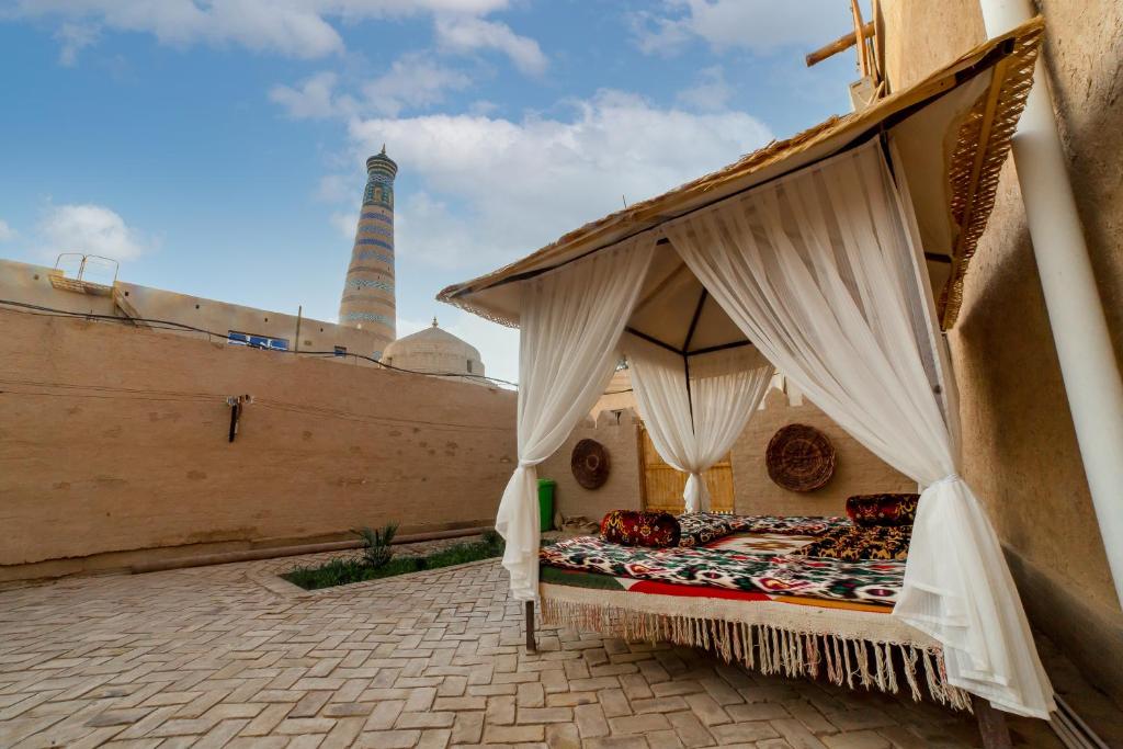 a bed in the courtyard of a building with a tower in the background at Islam Khodja in Khiva