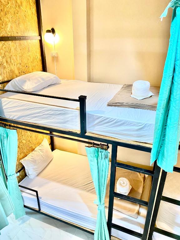 two bunk beds in a room with blue curtains at Khao Sok Inn Hostel in Khao Sok National Park